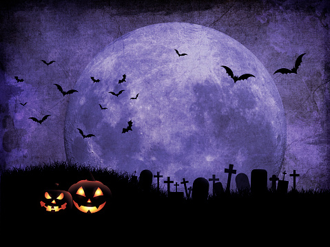 Grunge Halloween background with pumpkins in graveyard against moonlit sky