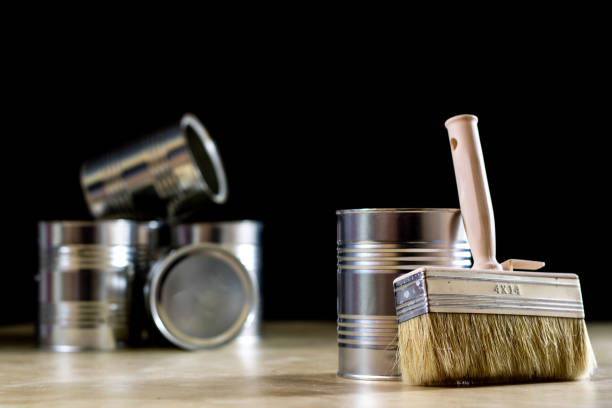 istock Cans of paint on a wooden workshop table. Next to the pedals and paint rollers. Black background 857100204