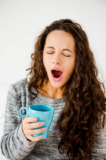 inizia una giornata con un caffè fresco - yawning women drink coffee cup foto e immagini stock