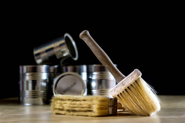 istock Cans of paint on a wooden workshop table. Next to the pedals and paint rollers. Black background 857104384