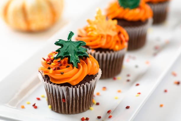 осенние вкусные кексы, украшенные оранжевой глазурью, красочными брызгами и кленовыми листьями - vegetable baked cake cup стоковые фото и изображения