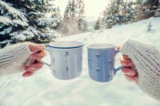 istock Couple hands in mittens take a mugs with hot tea in winter forest 857114580