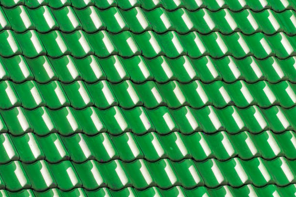 Green house roof tiles. Geometric pattern background image. Light and shade on vibrant colored curved tiles.