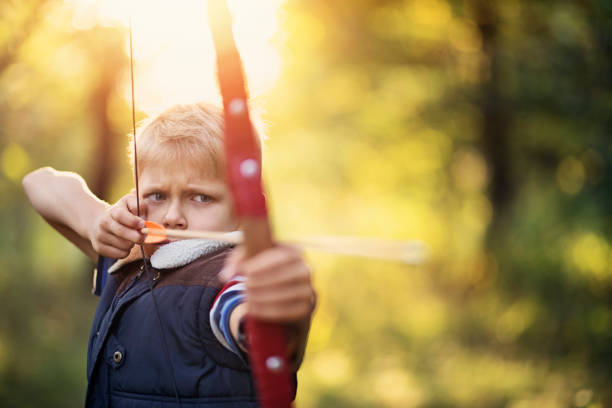 istock Little boy shooting bow in forest 857121918