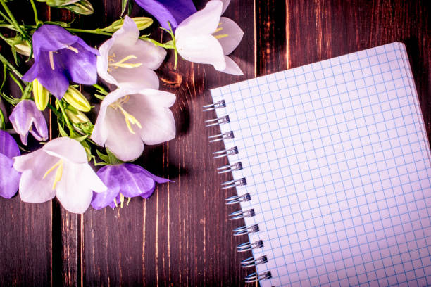 istock Spring flowers close-up with blank note book and copy space on wooden background. Spring summer border template. mock-up floral background. sale, greeting and celebration card concept. 857129720