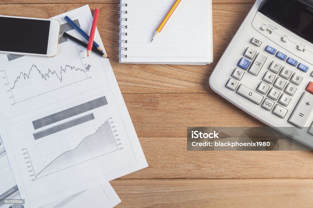 Grafik Investasi Dengan Laptop Dan Kalkulator Di Atas Meja Kayu Foto