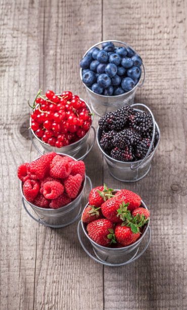 istock Berries overhead colorful mix in tin cans on wooden table 857138348