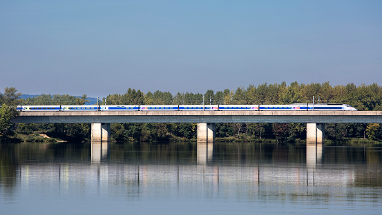 A French highspeed train TGV passes a bridge over River Saone nearby Macon. The Train a Grande Vitesse (high speed train) is France's high-speed rail service, it is operated by SNCF Voyages