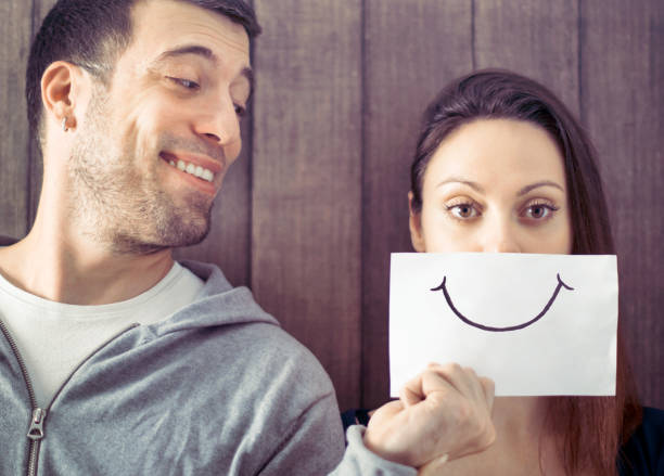 Friends making joke with a smile painted on paper