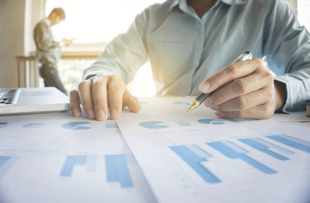istock Handsome young businessman working with laptop while sitting on the desk in office and financial statistic graph. 857145962