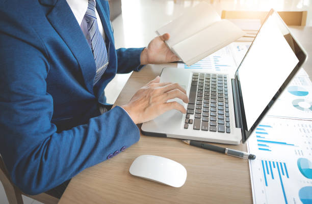 istock Business concept, Young business man's hands working with laptop and document graph, paper book on wood table. 857145970