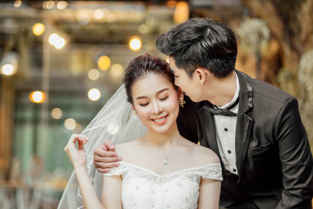 Asian couples are whispering and tell some sweet wording with smiling faces. stock photo