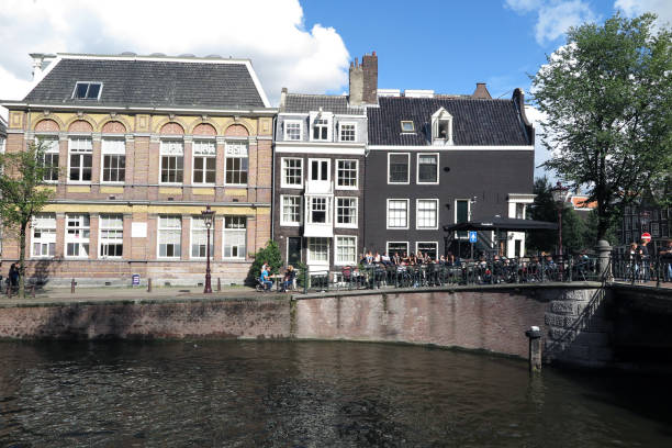 Amsterdam, Netherlands - September 9, 2017:  People enjoy the afternoon sun outside a bar and restaurant on the Prinsengracht Canal, also home to  Anne Frank's House and the Westerkerk.  The canals are one of Amsterdam's most popular attractions.