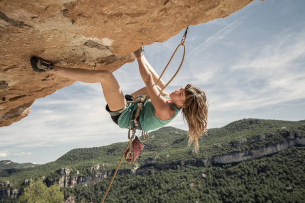 jovem mulher praticando escalada em rocha - climbing rock climbing women determination - fotografias e filmes do acervo