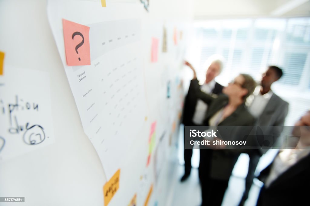 Productive Project Discussion of Colleagues Multi-ethnic team of talented white collar workers gathered together at marker board while having joint project discussion at spacious open plan office, focus on foreground Chalkboard - Visual Aid Stock Photo