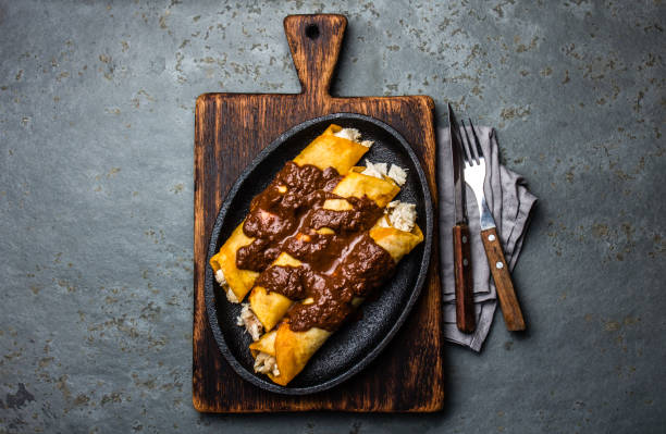 istock Mexican cuisine. Traditional Mexican chicken enchiladas with spicy chocolate salsa mole poblano. Enchiladas with sauce moole from Puebla, Mexico 857179228