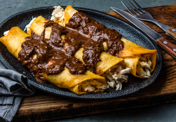 Mexican cuisine. Traditional Mexican chicken enchiladas with spicy chocolate salsa mole poblano. Enchiladas with sauce moole from Puebla, Mexico