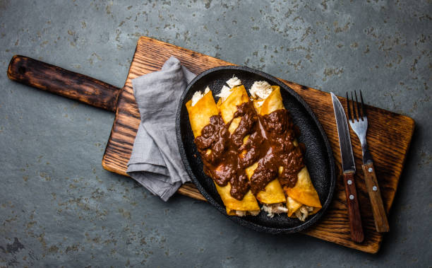 Mexican cuisine. Traditional Mexican chicken enchiladas with spicy chocolate salsa mole poblano. Enchiladas with sauce moole from Puebla, Mexico