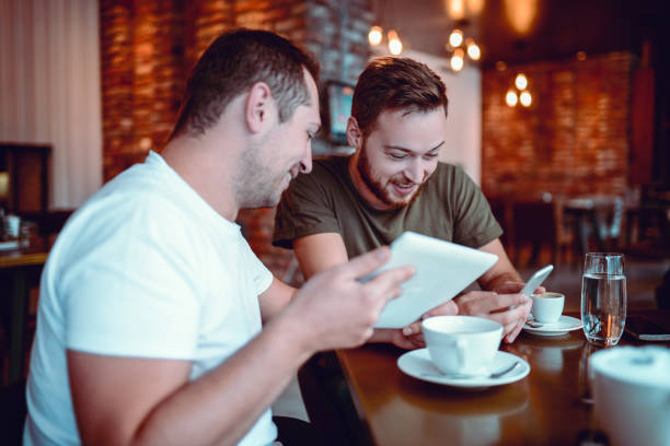 istock Two Smiling  Male Freelancers Drinking Coffee and Working In Cafe Restaurant 857197202
