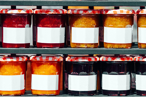 Rows of jars with orange jams, blueberries and strawberries