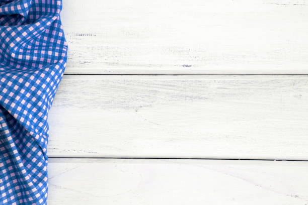istock Crumpled blue checkered tablecloth or napkin on empty white wooden table with copy space for food cooking  menu background concept , top view or overhead shot 857228848