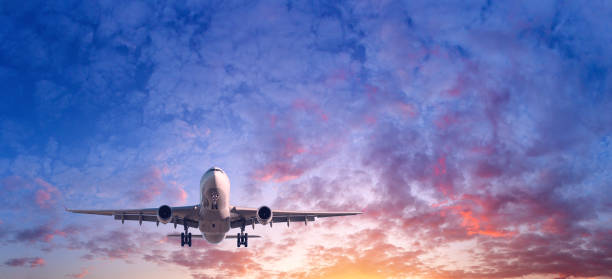 着陸飛行機。乗客の飛行機のある風景が日没時赤、紫とオレンジ色の雲と青空に飛んでいます。背景を旅行します。乗客の定期旅客機。民間航空機。プライベート ジェット - airport airplane landing red ストックフォトと画像