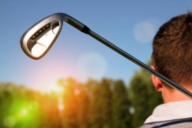 Portrait of golf player taking a shot on black background