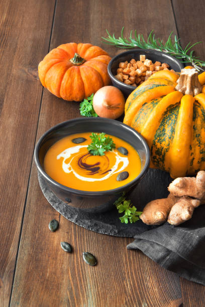 唐辛子とにんにくでピリ辛かぼちゃスープが暗いボウルでお召し上がりいただけます - pumpkin soup ストックフォトと画像