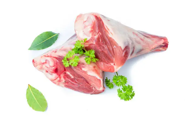 Fresh red meat, lamb shank raw, chops isolated on white, garnished with parsley.