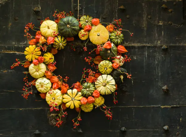 Photo of Handmade wreath of small pumpkins and zucchini on a vintage door