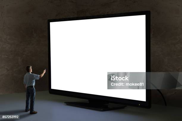 Man Pointing Tv Remote Control At Worlds Biggest Giant Television With Blank Screen Stock Photo - Download Image Now