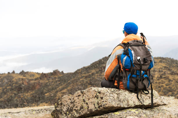 istock A lonely tourist with a backpack and in sunglasses is resting sitting on a rock 857259636