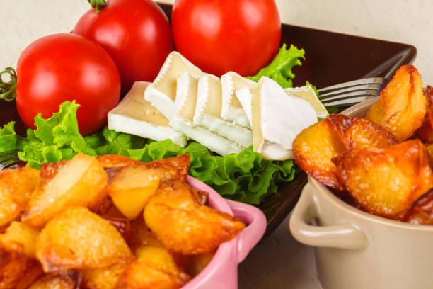 Breakfast from cheese, tomatoes, potatoes and all-over salad on a wooden table closeup.