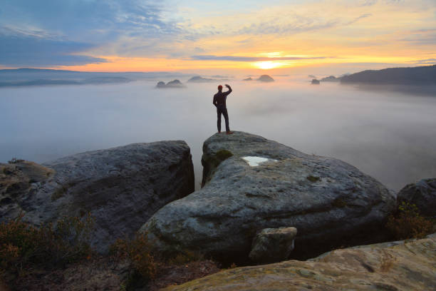 istock Sharp rear man silhouette on rocky peak. Satisfy hiker enjoy view. Tall man on rocky cliff 857275274