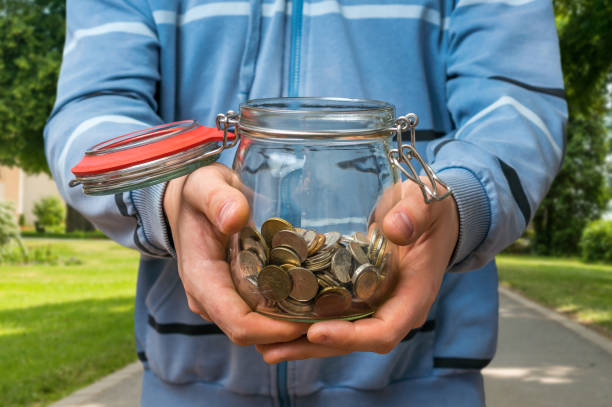 istock Man in blue sweatshirt holding money jar with coins 857280948