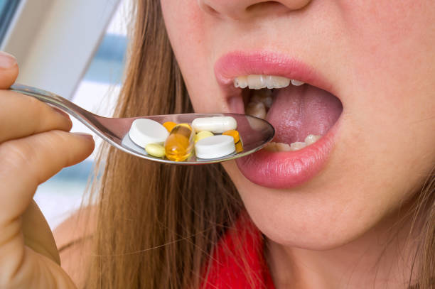 istock Young woman eating pills on a spoon 857282978