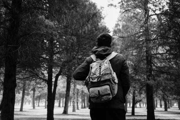 Young traveler trekking into the woods with backpack along the path (Black and White tone)