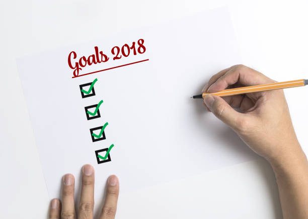 istock Hand writing down checklists for 2018 Goals on paper top view copy space 857292438