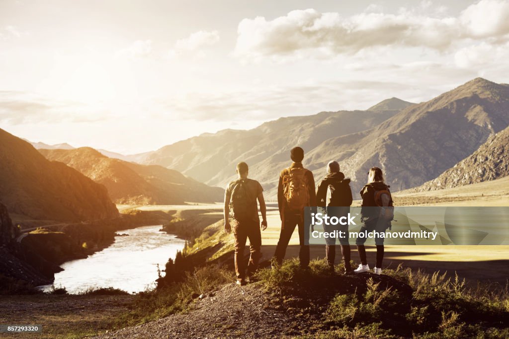 Group four people mountains travel concept Group of four people stands on mountains and river backdrop. Travel expedition trekking concept with space for text Hiking Stock Photo