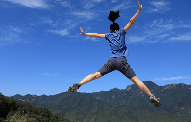 istock successful woman hiker jumping on mountain top 857297298