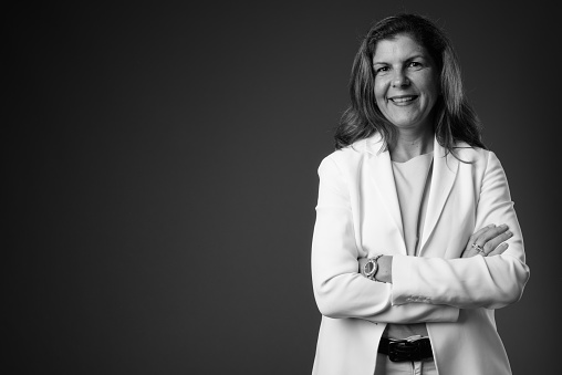 Studio shot of mature businesswoman wearing pant suit against gray background horizontal shot