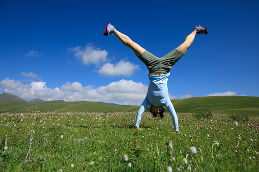 woman doing a handstand in a mountain peak meadow