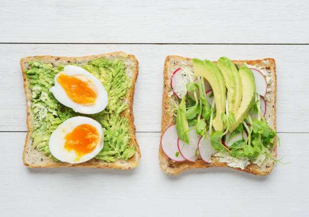 istock Two avocado toasts on white wooden background 857308674
