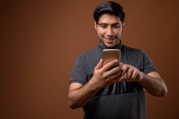 istock Studio shot of young handsome Iranian man using mobile phone against colored background 857308926