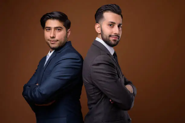 Photo of Studio shot of young handsome Iranian brothers against colored background