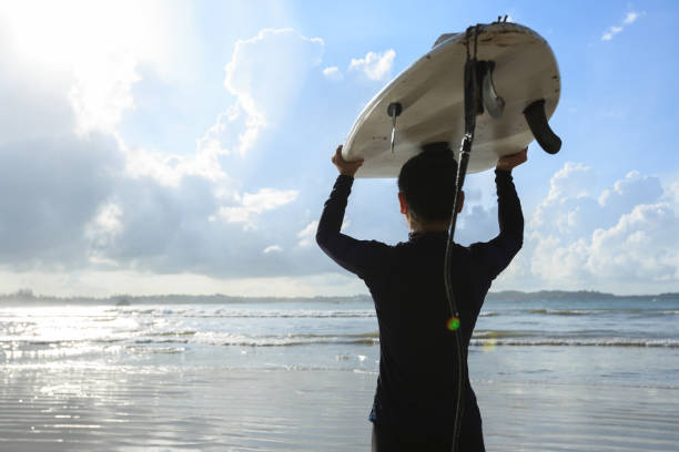 istock woman surfer with white surfboard warlking to the wave 857317382