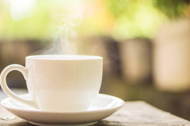 istock hot coffee cup under sunrise in background, vintage tone 857319034
