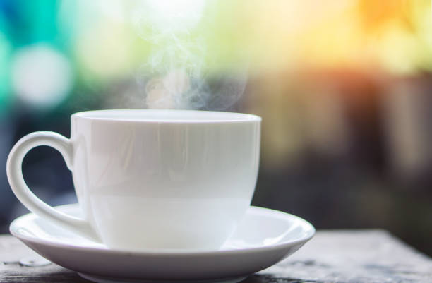 istock hot coffee cup under sunrise in background, vintage tone 857323688
