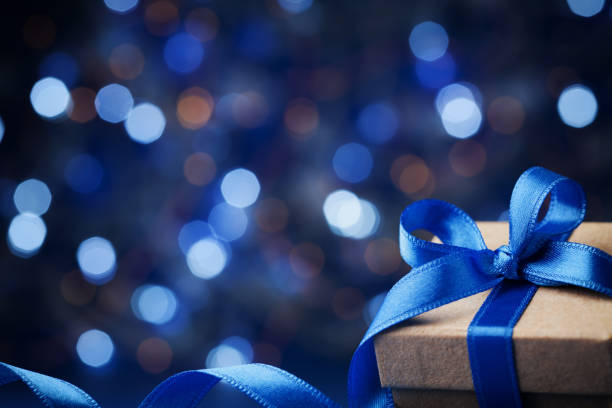 istock Christmas gift box or present with bow ribbon on magic blue bokeh background. 857324902
