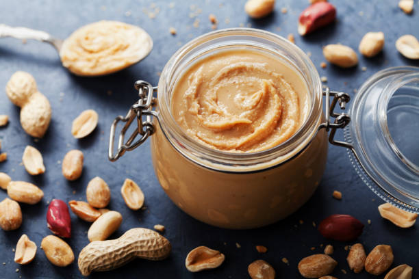 istock Peanut butter jar and heap of nuts on vintage table. 857325150